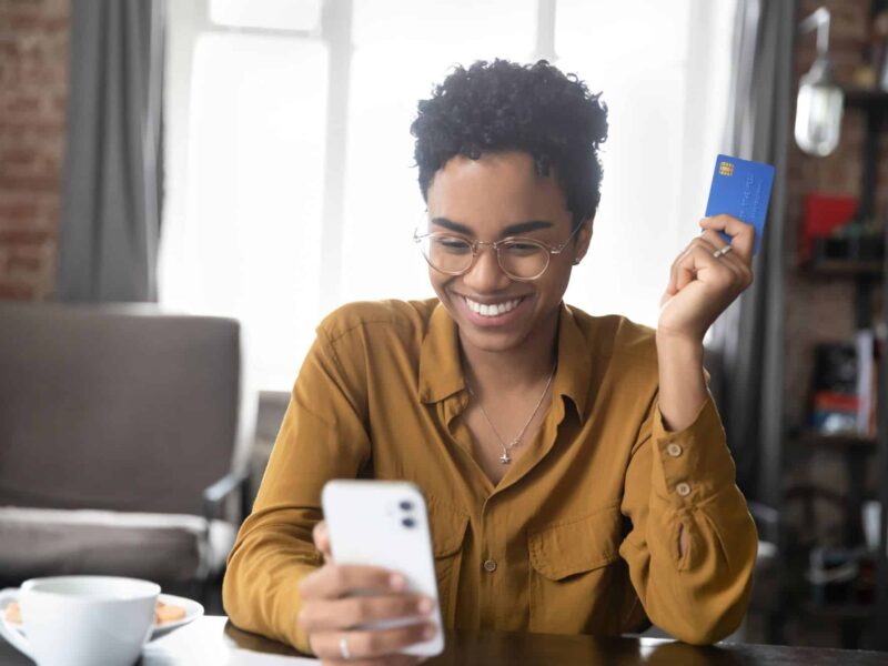 Woman smiling with card out looking at phone