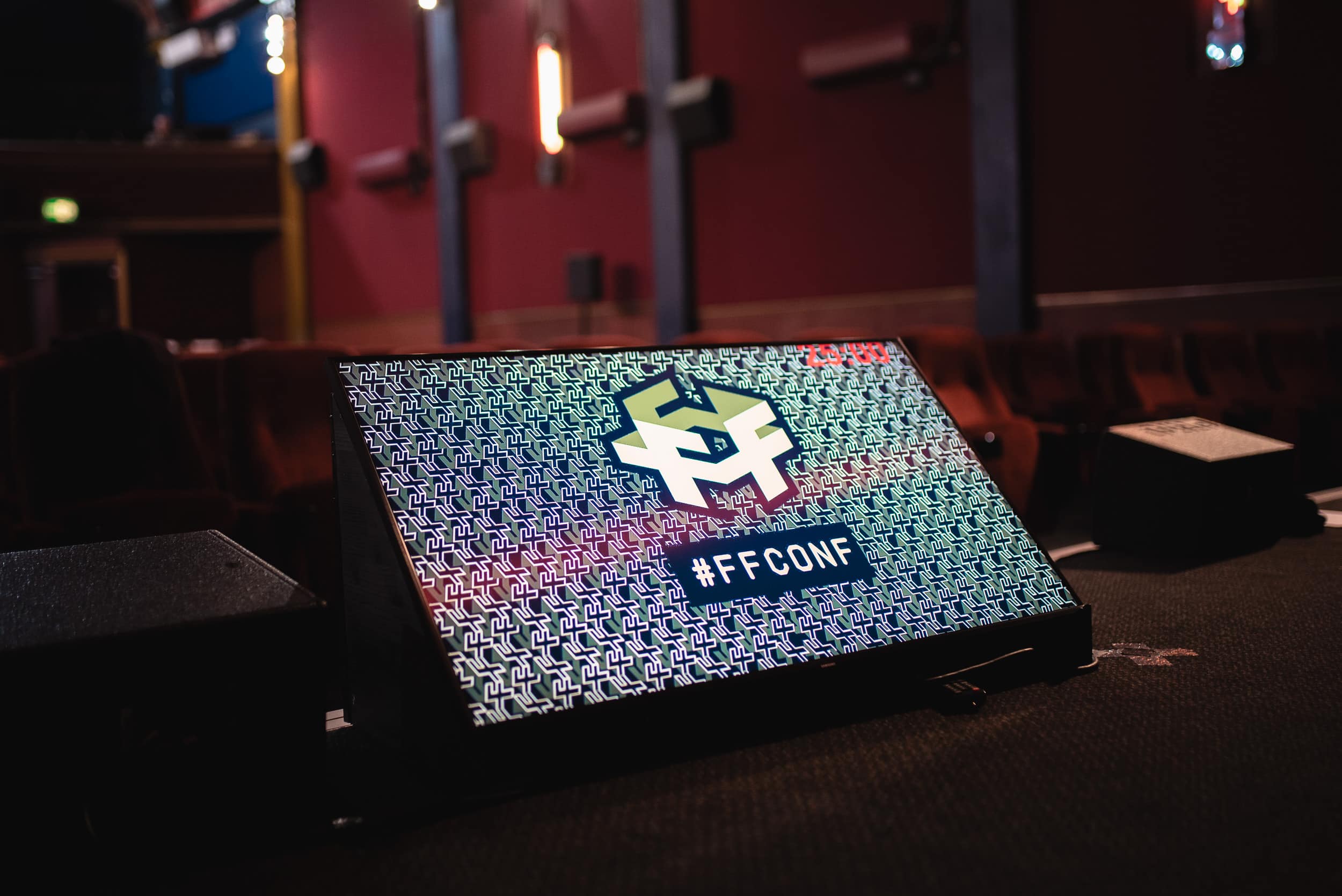 A screen on a stage with the ffconf logo and hashtag