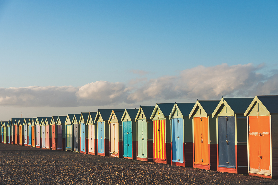 Row of multicoloured English beach huts on Brighton beach in the evening sun