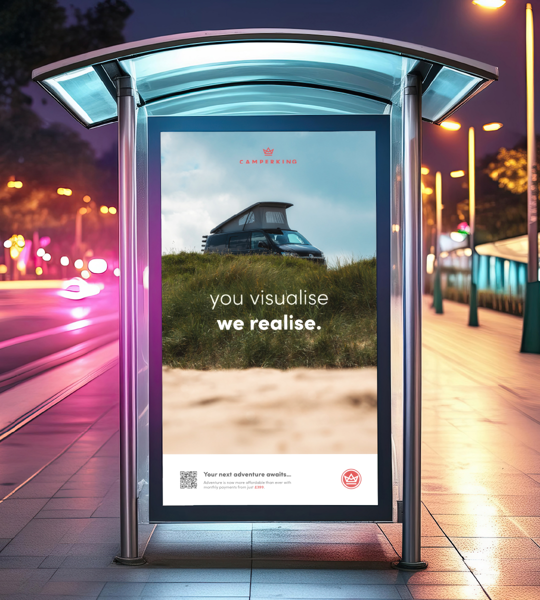 A bus stop at night with a Camperking advertisement light up on the side of it