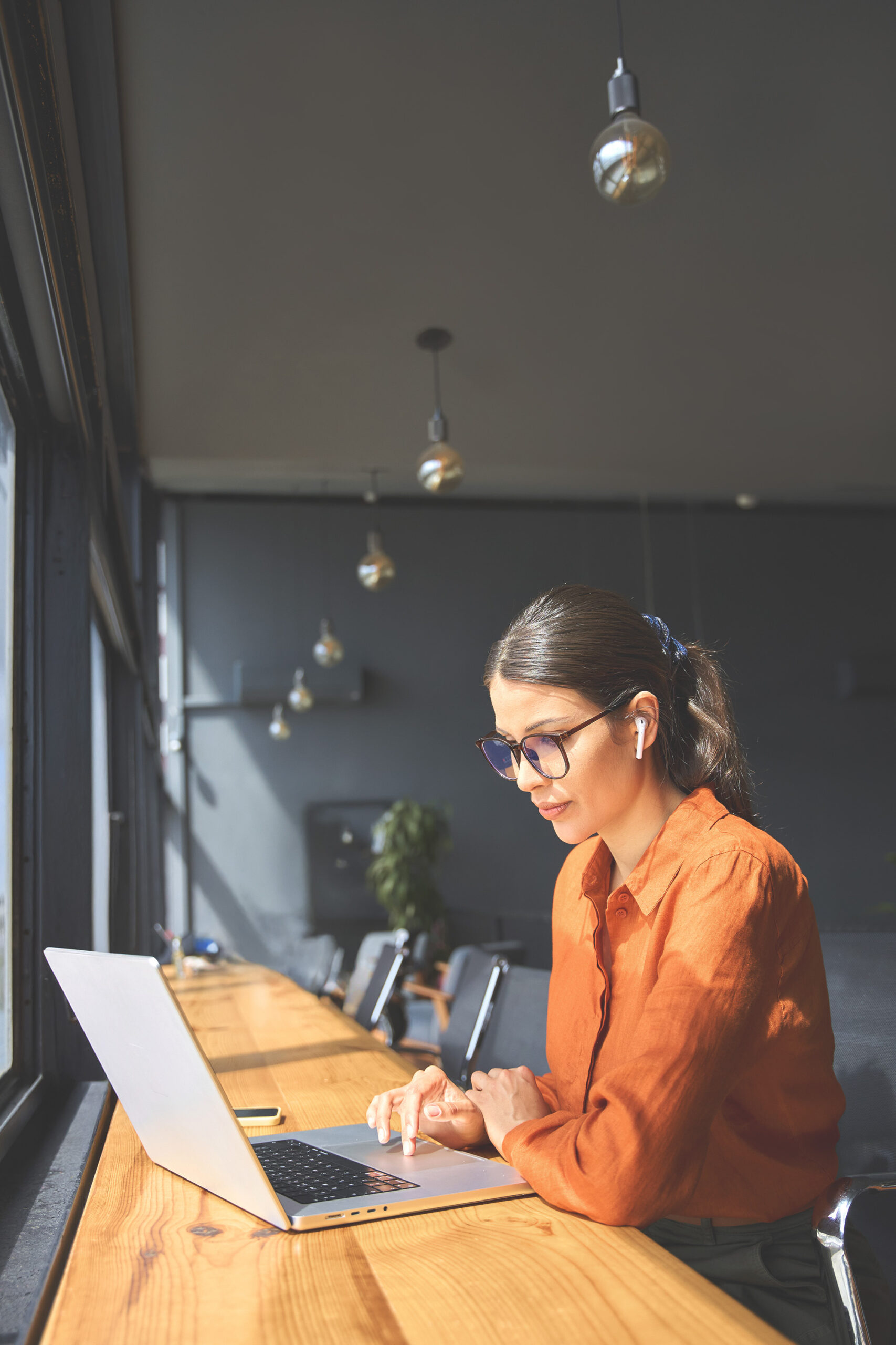 woman in glasses doing data analysis at a laptop in a modern office setting