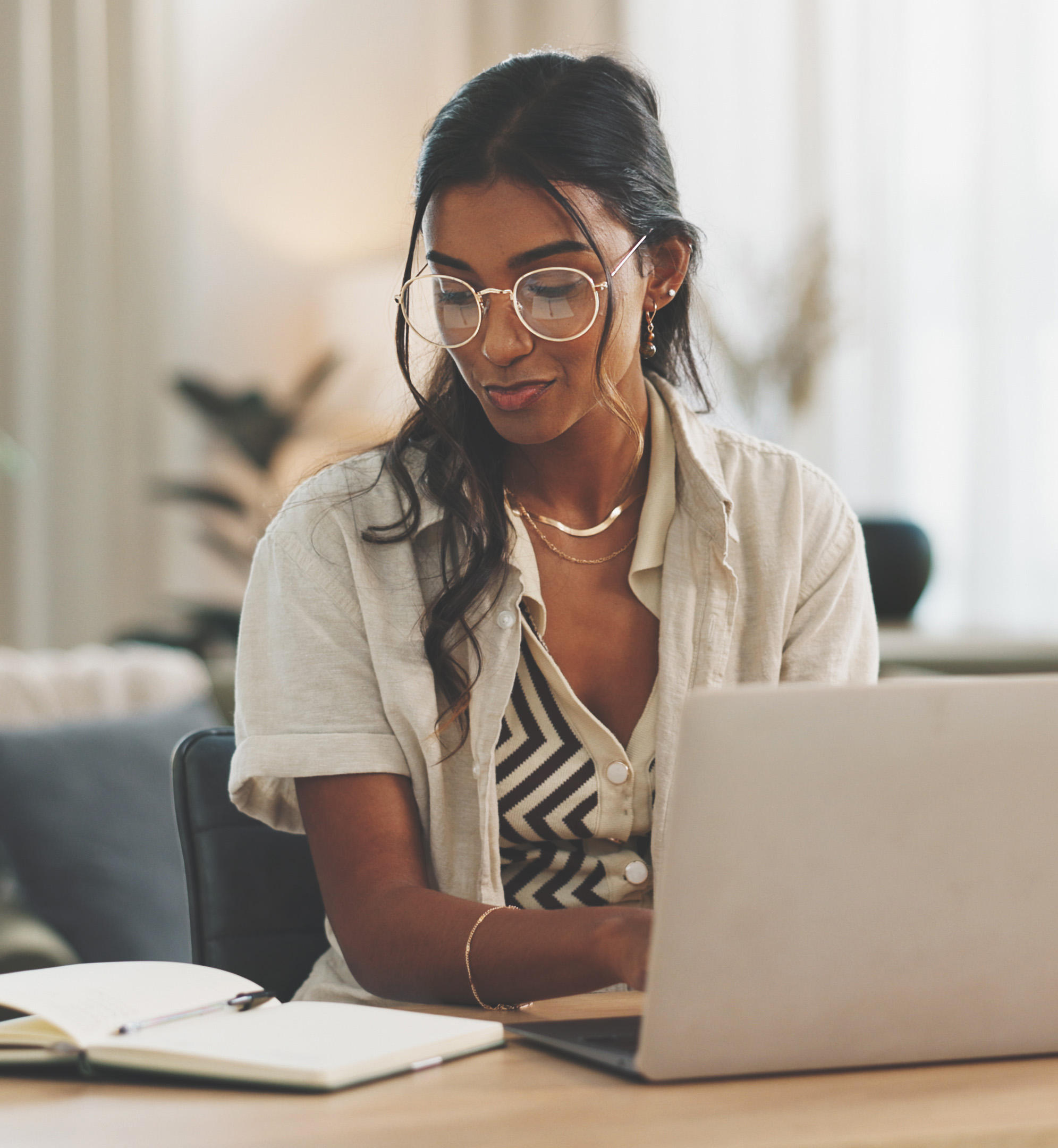 woman writing content on laptop with notebook