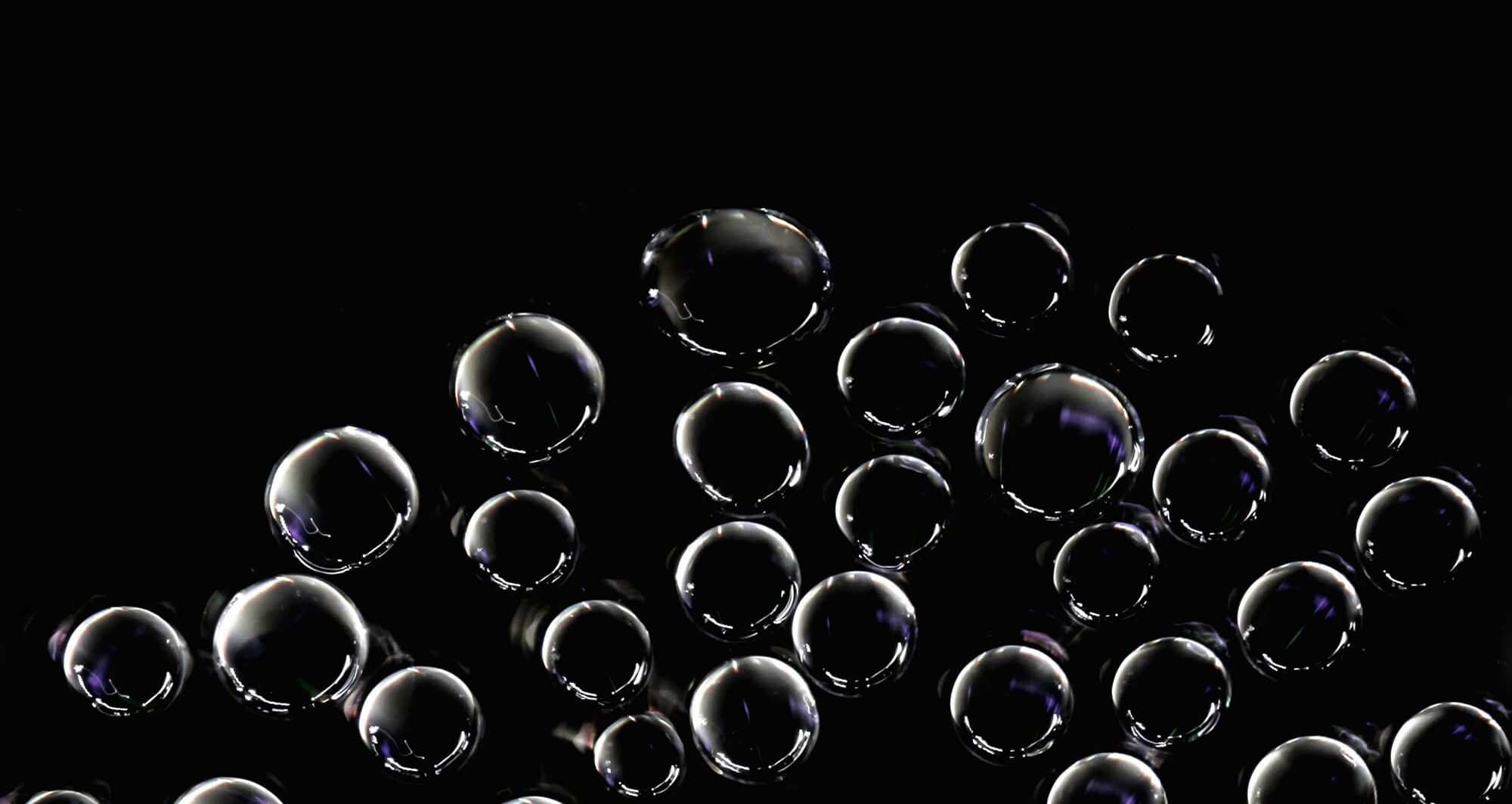 Transparent bubbles floating against a dark background, symbolising the potential burst of the AI technology bubble