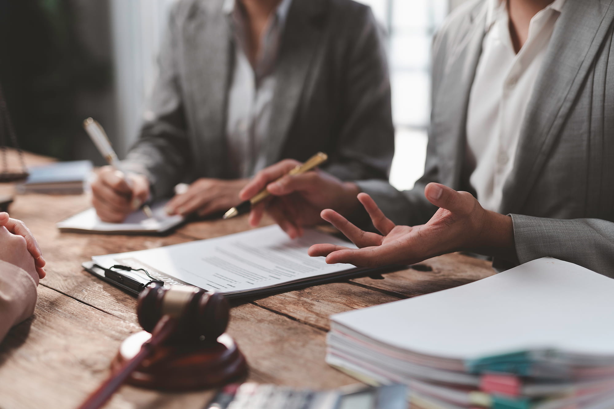 Lawyers discussing documents at a desk with a gavel nearby.
