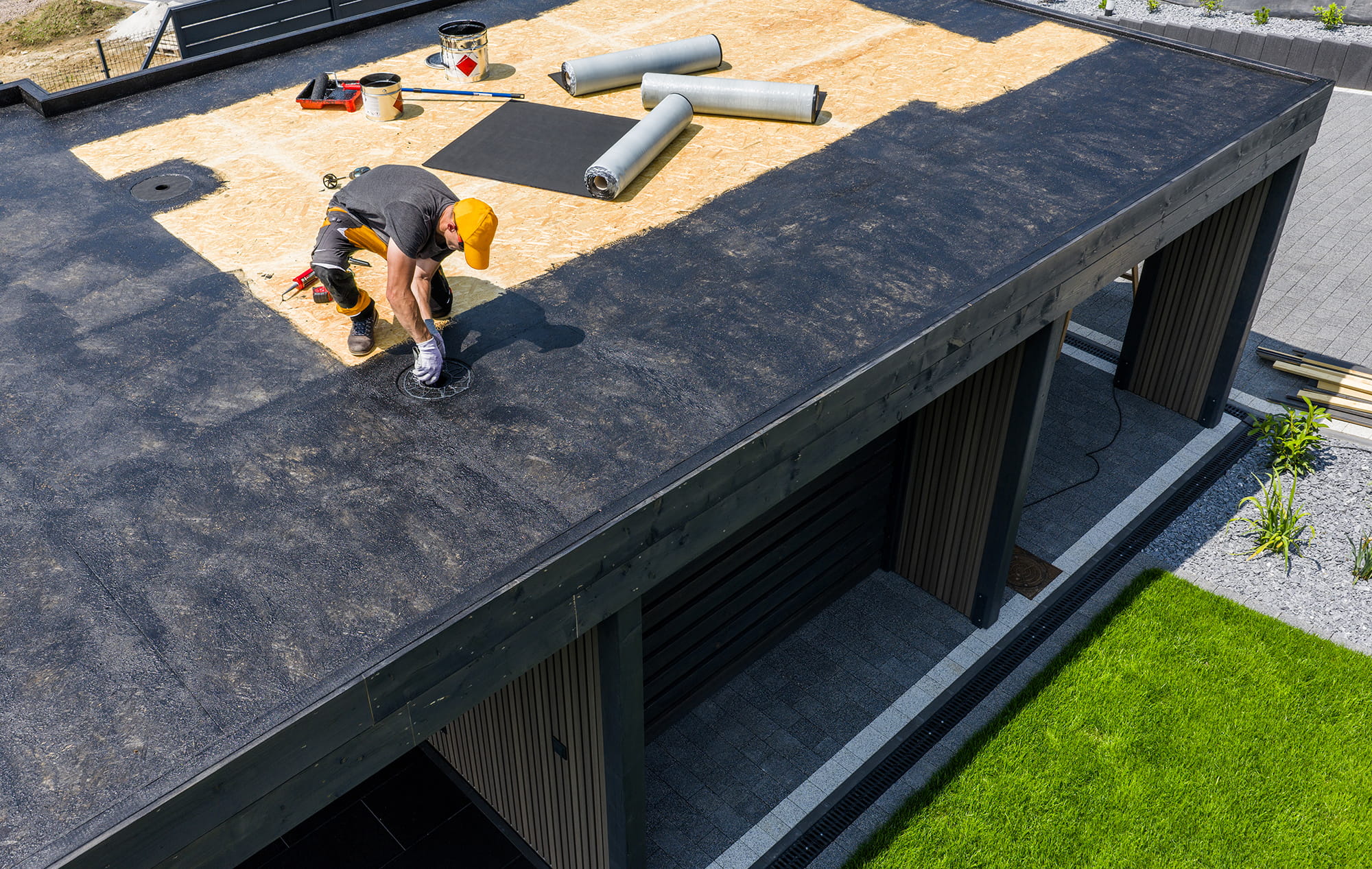 Worker installing rubber roofing membrane on a flat roof.