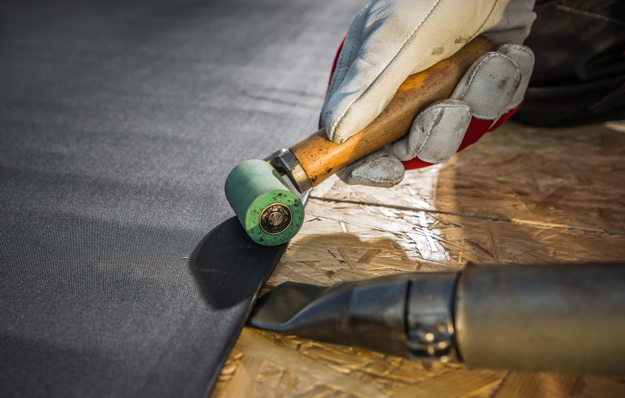 Close-up of sealing rubber membrane with a hand roller tool.